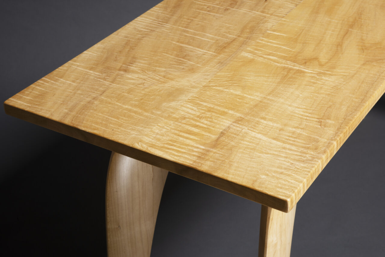 detail of top of solid maple hall table with figured top and sculpted legs by Seth Rolland Custom Furniture